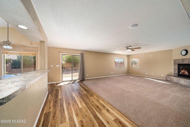 unfurnished living room featuring ceiling fan, wood-type flooring, a textured ceiling, and a fireplace