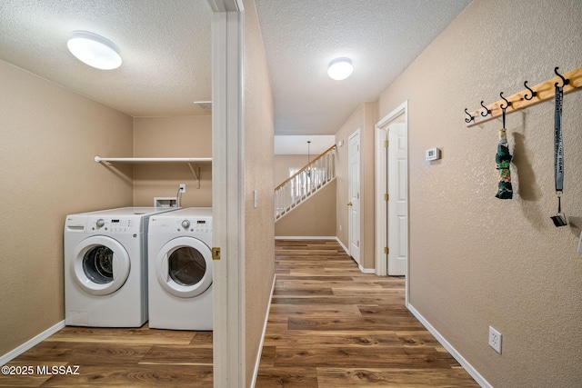 washroom with separate washer and dryer, hardwood / wood-style floors, and a textured ceiling