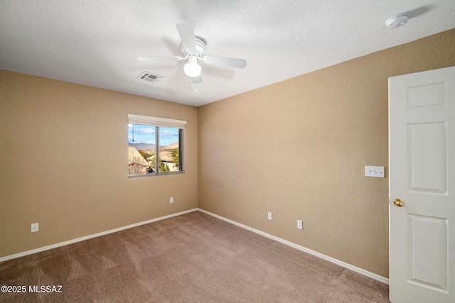 carpeted spare room with a textured ceiling and ceiling fan