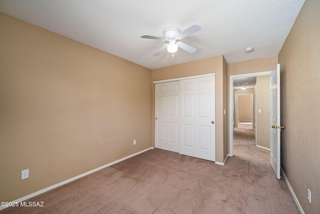 unfurnished bedroom featuring light colored carpet, a textured ceiling, ceiling fan, and a closet