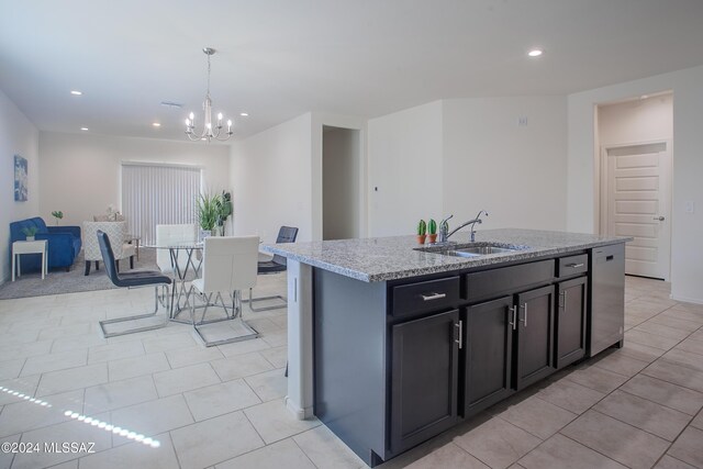 kitchen with light stone countertops, sink, a kitchen island with sink, a chandelier, and light tile patterned floors