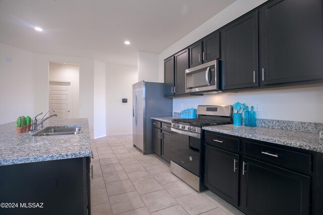 kitchen with a kitchen bar, light tile patterned flooring, a kitchen island with sink, stainless steel appliances, and light stone counters