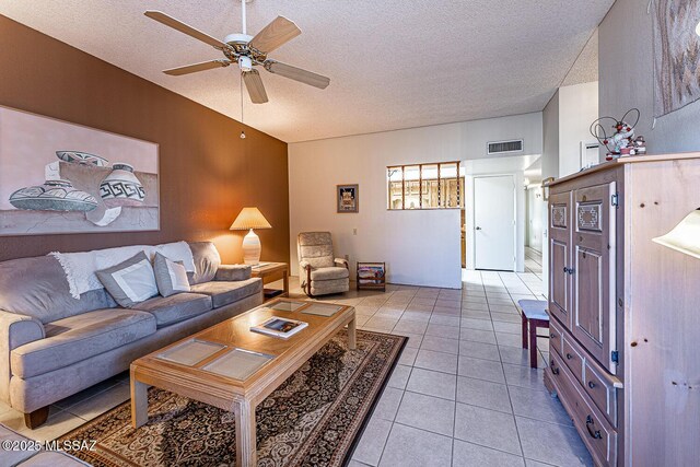 living room with a textured ceiling, ceiling fan, and light tile patterned floors