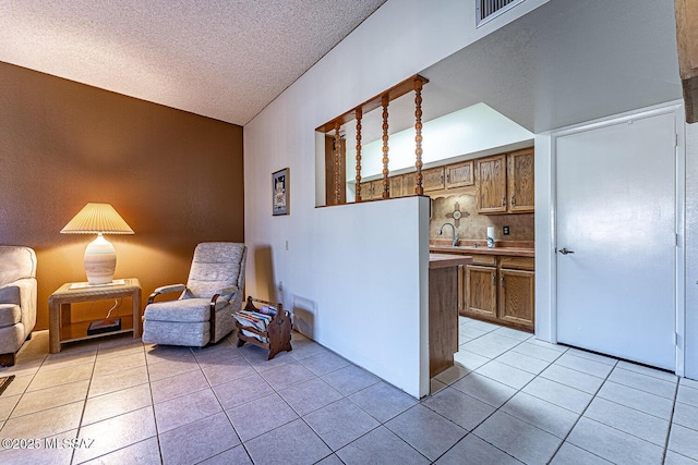 sitting room with a textured ceiling, sink, and light tile patterned floors