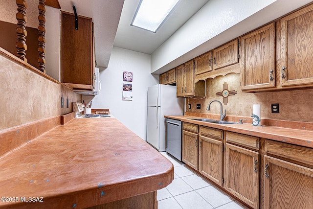 kitchen with stainless steel dishwasher, range, white fridge, light tile patterned floors, and sink