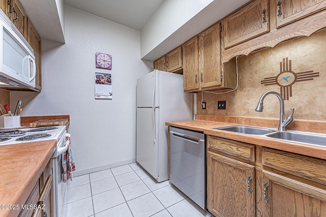 kitchen with white appliances, sink, and light tile patterned floors