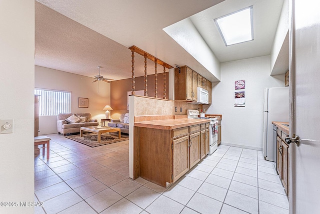 kitchen featuring a textured ceiling, white appliances, ceiling fan, light tile patterned floors, and backsplash