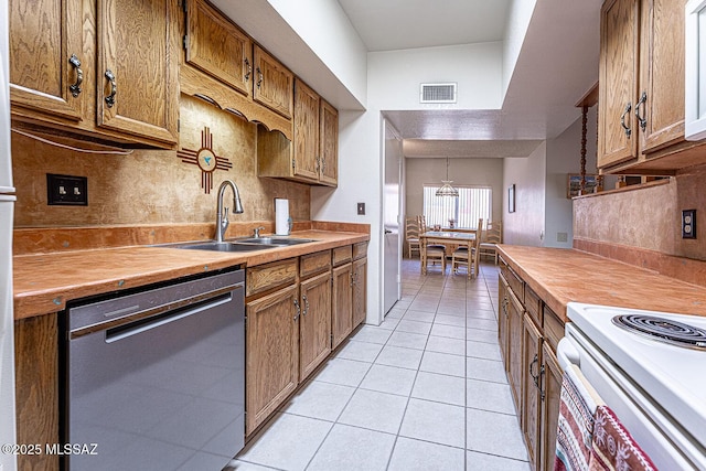 kitchen featuring light tile patterned floors, a notable chandelier, decorative backsplash, sink, and black dishwasher