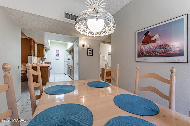 tiled dining area featuring an inviting chandelier and a textured ceiling