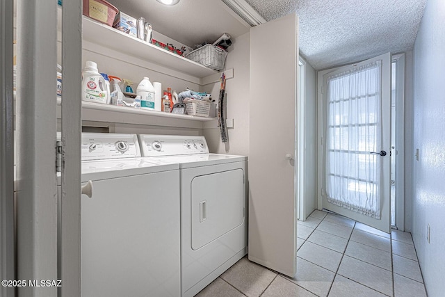 laundry room with a textured ceiling, washing machine and clothes dryer, and light tile patterned floors