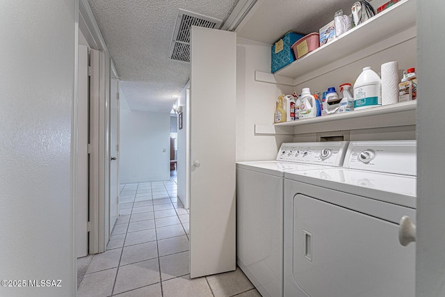 washroom with a textured ceiling, light tile patterned floors, and independent washer and dryer