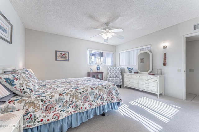 bedroom with a textured ceiling, ceiling fan, and light carpet