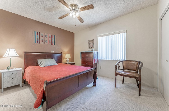 bedroom featuring a closet, ceiling fan, a textured ceiling, and light colored carpet