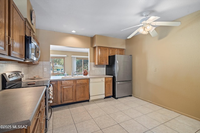 kitchen featuring sink, backsplash, light tile patterned floors, ceiling fan, and stainless steel appliances