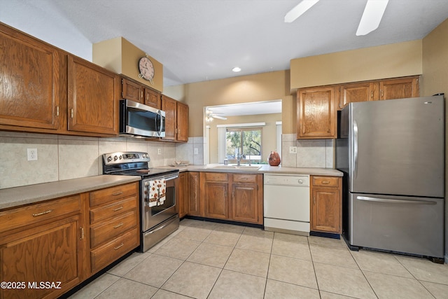 kitchen with light tile patterned flooring, appliances with stainless steel finishes, ceiling fan, and decorative backsplash