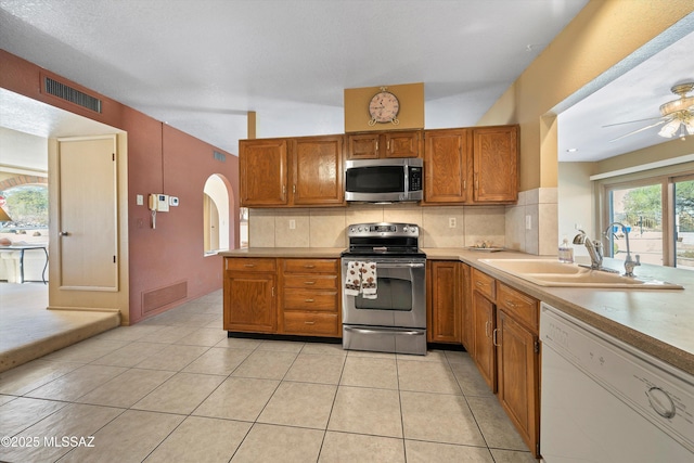 kitchen with appliances with stainless steel finishes, kitchen peninsula, sink, and decorative backsplash