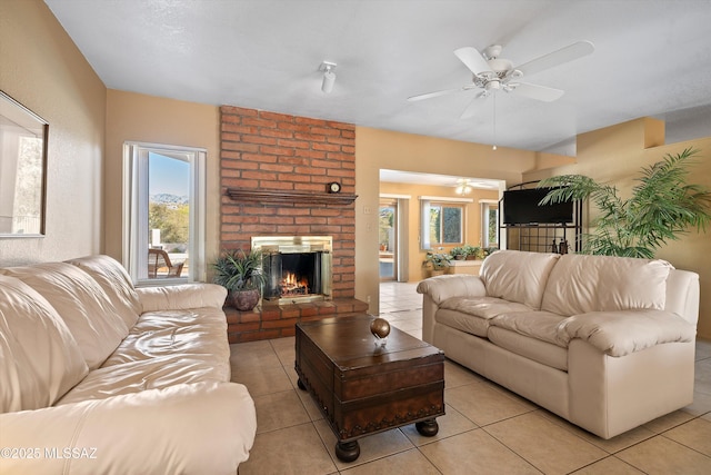 tiled living room with ceiling fan and a fireplace