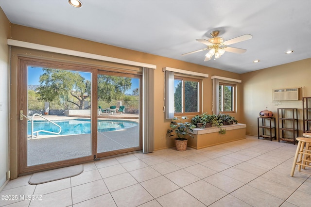 doorway to outside with a wall unit AC, a healthy amount of sunlight, light tile patterned floors, and ceiling fan