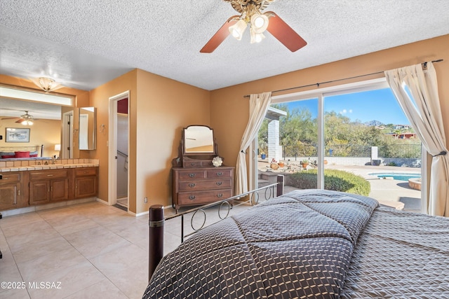 tiled bedroom featuring ceiling fan, connected bathroom, sink, and a textured ceiling