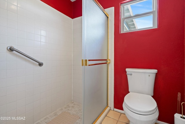 bathroom featuring a shower with door, tile patterned flooring, and toilet