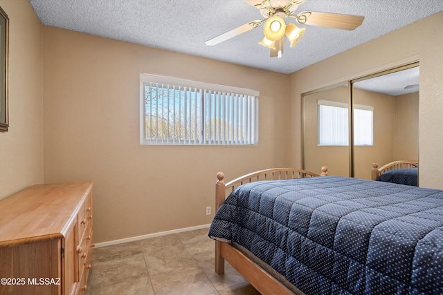 tiled bedroom featuring a textured ceiling, ceiling fan, and a closet