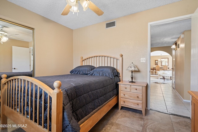 tiled bedroom with ceiling fan and a textured ceiling