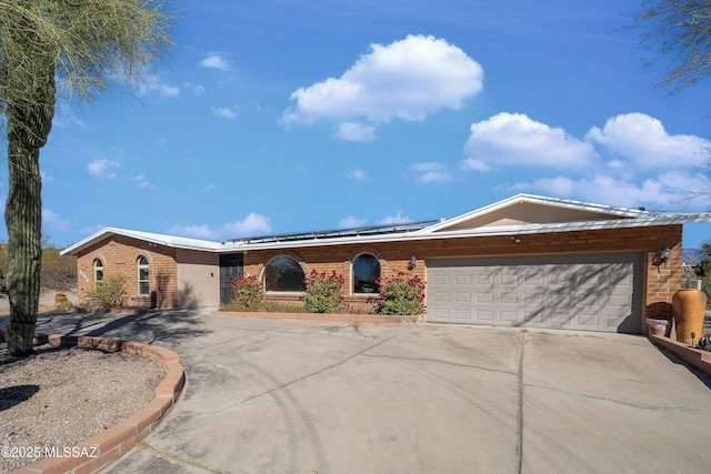 ranch-style house with a garage and solar panels