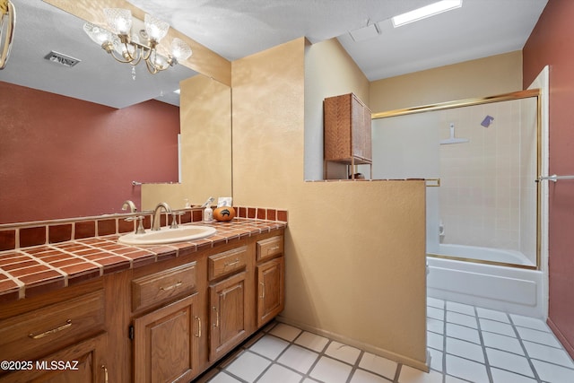 bathroom featuring tile patterned flooring, bath / shower combo with glass door, a notable chandelier, and vanity