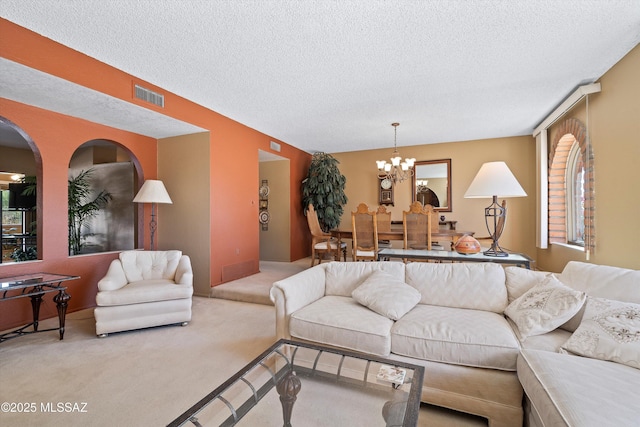 carpeted living room featuring a textured ceiling and a notable chandelier