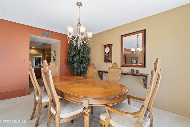 carpeted dining area with an inviting chandelier and a textured ceiling