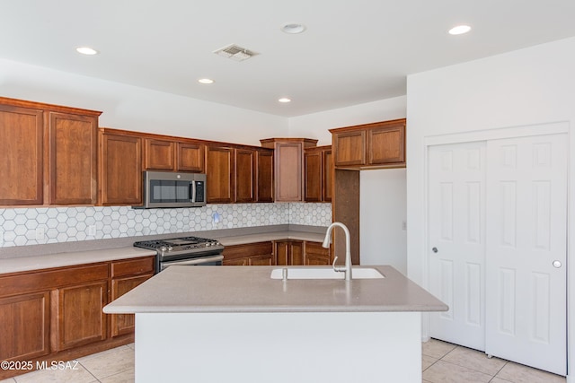 kitchen with visible vents, brown cabinets, a sink, stainless steel appliances, and light tile patterned flooring