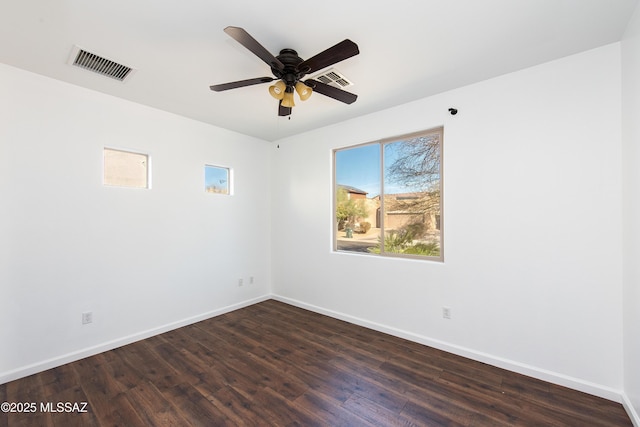 unfurnished room with ceiling fan, dark wood-style floors, visible vents, and baseboards