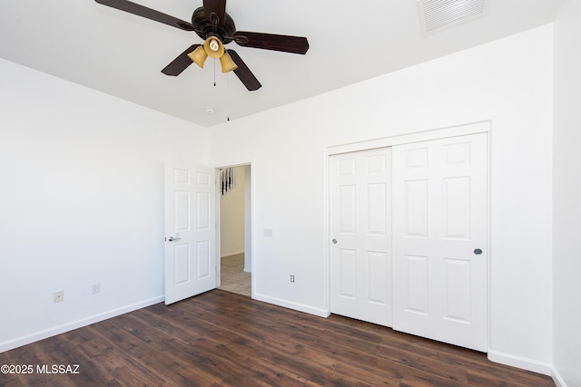 unfurnished bedroom featuring baseboards, visible vents, dark wood finished floors, ceiling fan, and a closet