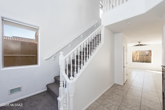 staircase featuring tile patterned floors, visible vents, baseboards, and ceiling fan