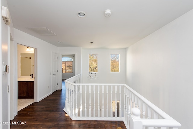 corridor featuring dark wood-style floors, an upstairs landing, a healthy amount of sunlight, and visible vents