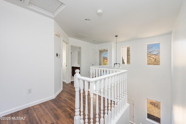 corridor featuring attic access, dark wood-style floors, an upstairs landing, and baseboards