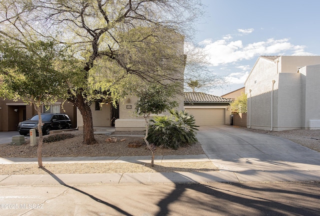 view of front facade featuring stucco siding, a tiled roof, concrete driveway, and a garage