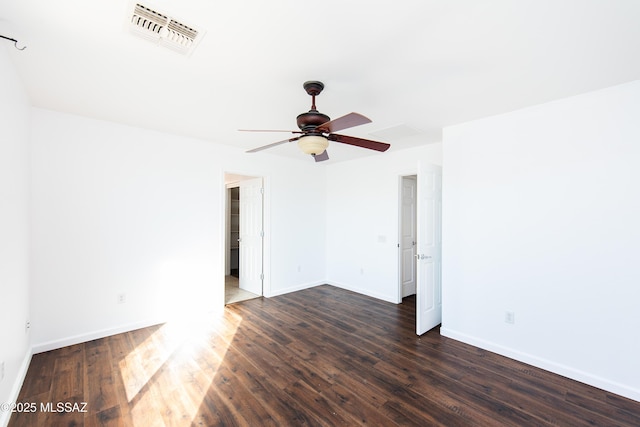 spare room featuring dark wood finished floors, visible vents, a ceiling fan, and baseboards