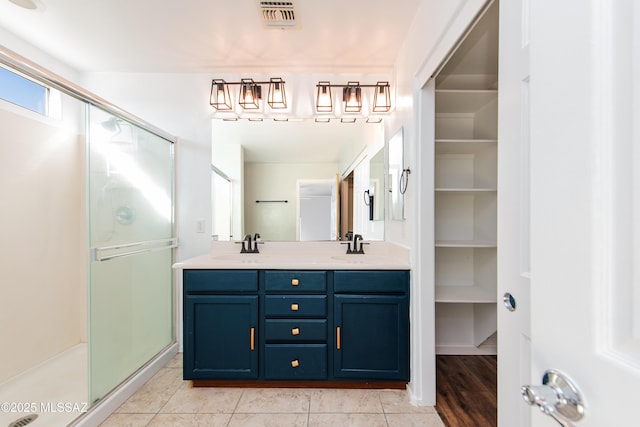 full bathroom featuring a shower stall, double vanity, visible vents, and a sink