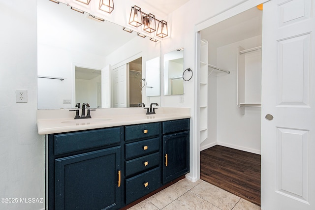 full bathroom with double vanity, tile patterned floors, baseboards, and a sink