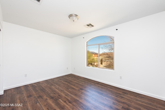 empty room featuring visible vents, baseboards, and wood finished floors