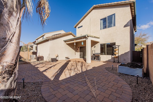 rear view of property with stucco siding, a patio, and a fenced backyard