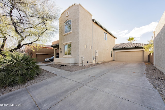 view of home's exterior with concrete driveway, an attached garage, a tile roof, and stucco siding