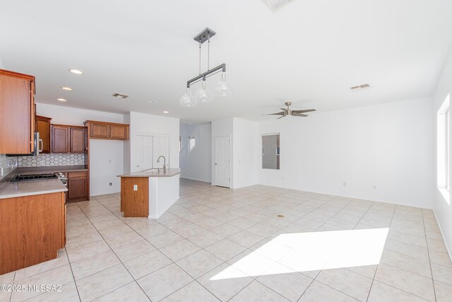 kitchen featuring ceiling fan, dishwashing machine, decorative light fixtures, a kitchen island with sink, and sink