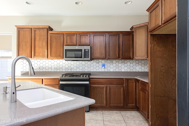 kitchen featuring light tile patterned floors, range with gas cooktop, tasteful backsplash, and sink