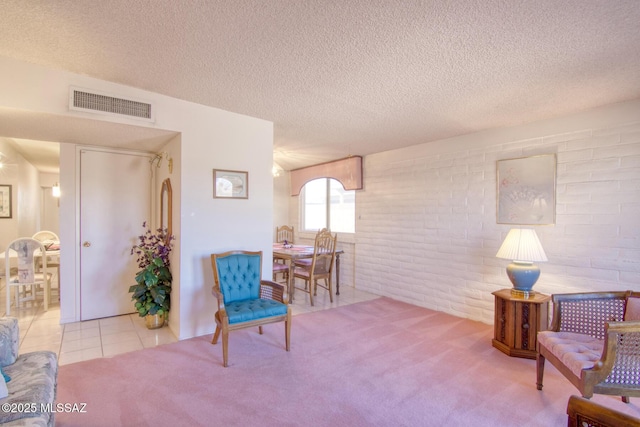 living area featuring brick wall, a textured ceiling, and light carpet