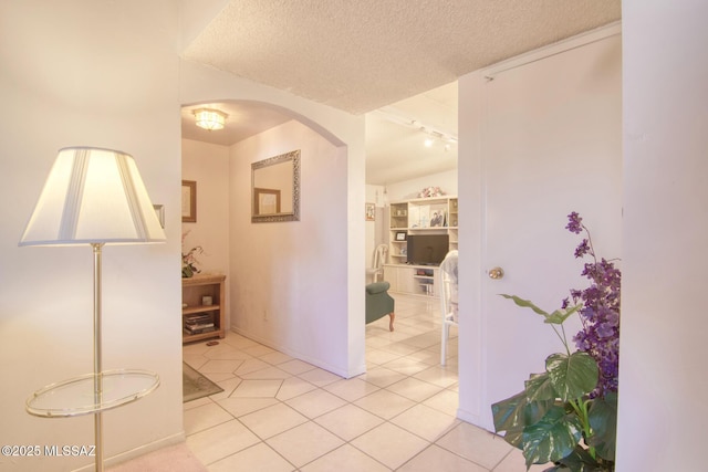 corridor with a textured ceiling and light tile patterned floors