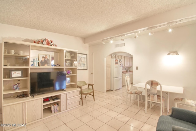 living room with a textured ceiling, light tile patterned flooring, and track lighting