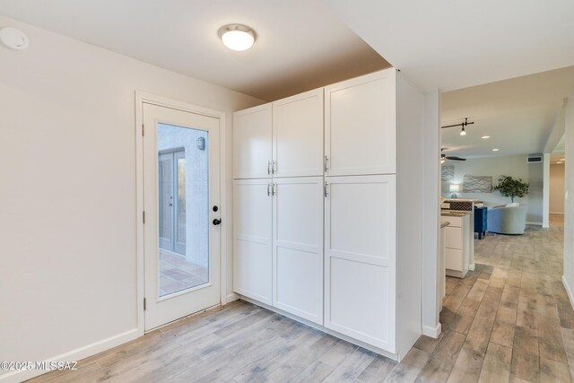 clothes washing area with washer and dryer, light wood-type flooring, and a skylight