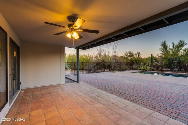 pool at dusk featuring a lawn and a patio area